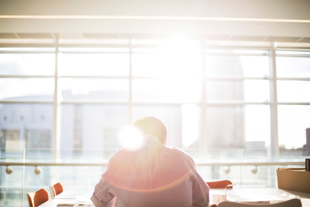 A person sits at a clean, modern desk with papers and a pen, thoughtfully planning for the future, illuminated by warm, natural light.