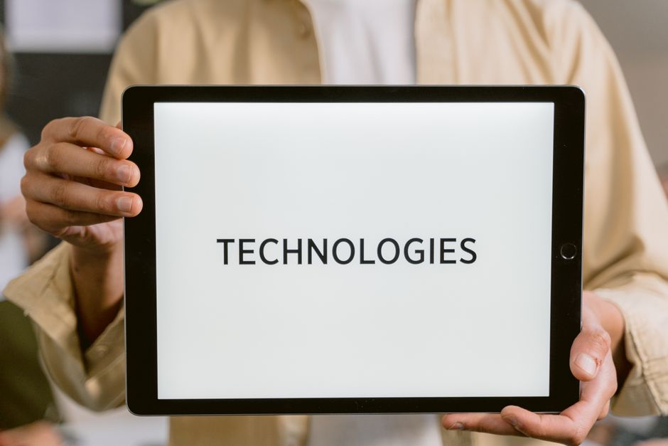 A broker holds a digital tablet displaying glowing architectural lines, illustrating the intersection of AI technology and real estate marketing.