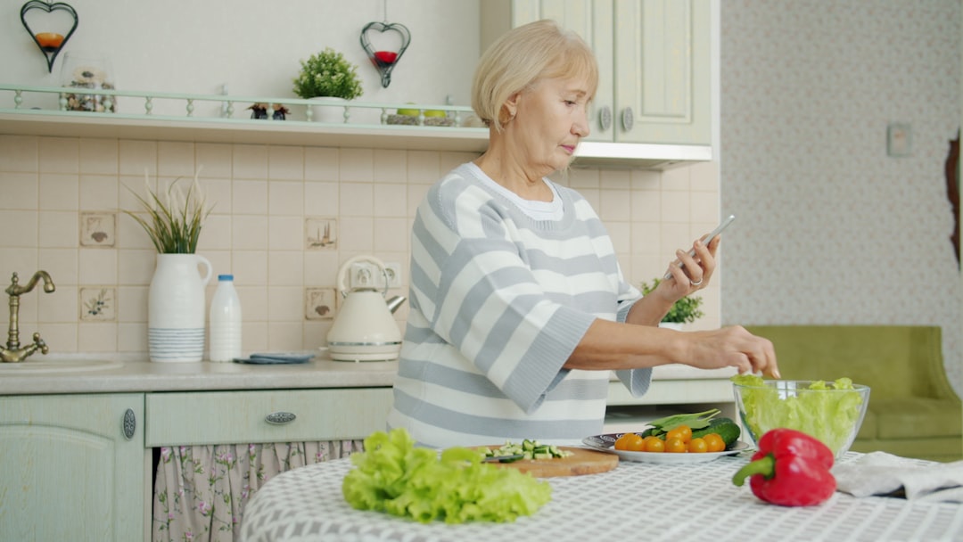 An overhead shot of a person's hands chopping colorful, fresh vegetables on a wooden board in a bright, modern kitchen, symbolizing daily healthy nutrition choices.