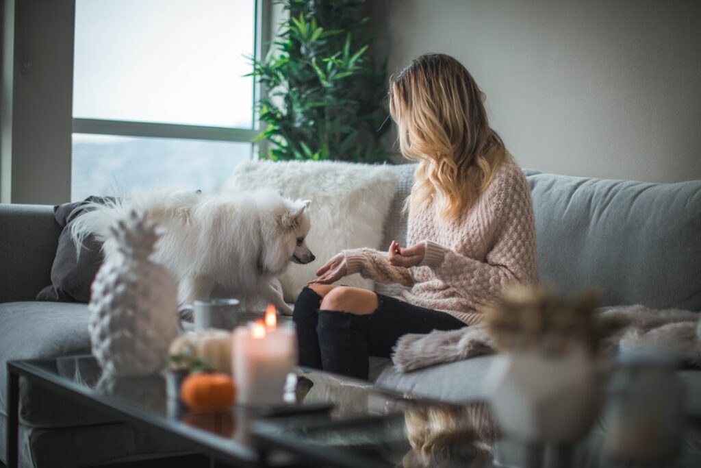 Woman sits peacefully in a cross-legged position on a yoga mat in her sunlit, minimalist living room, embodying a moment o...